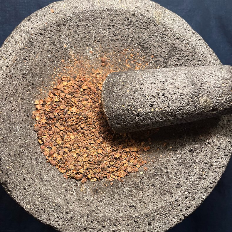 Mortar and pestle grinding up allspice