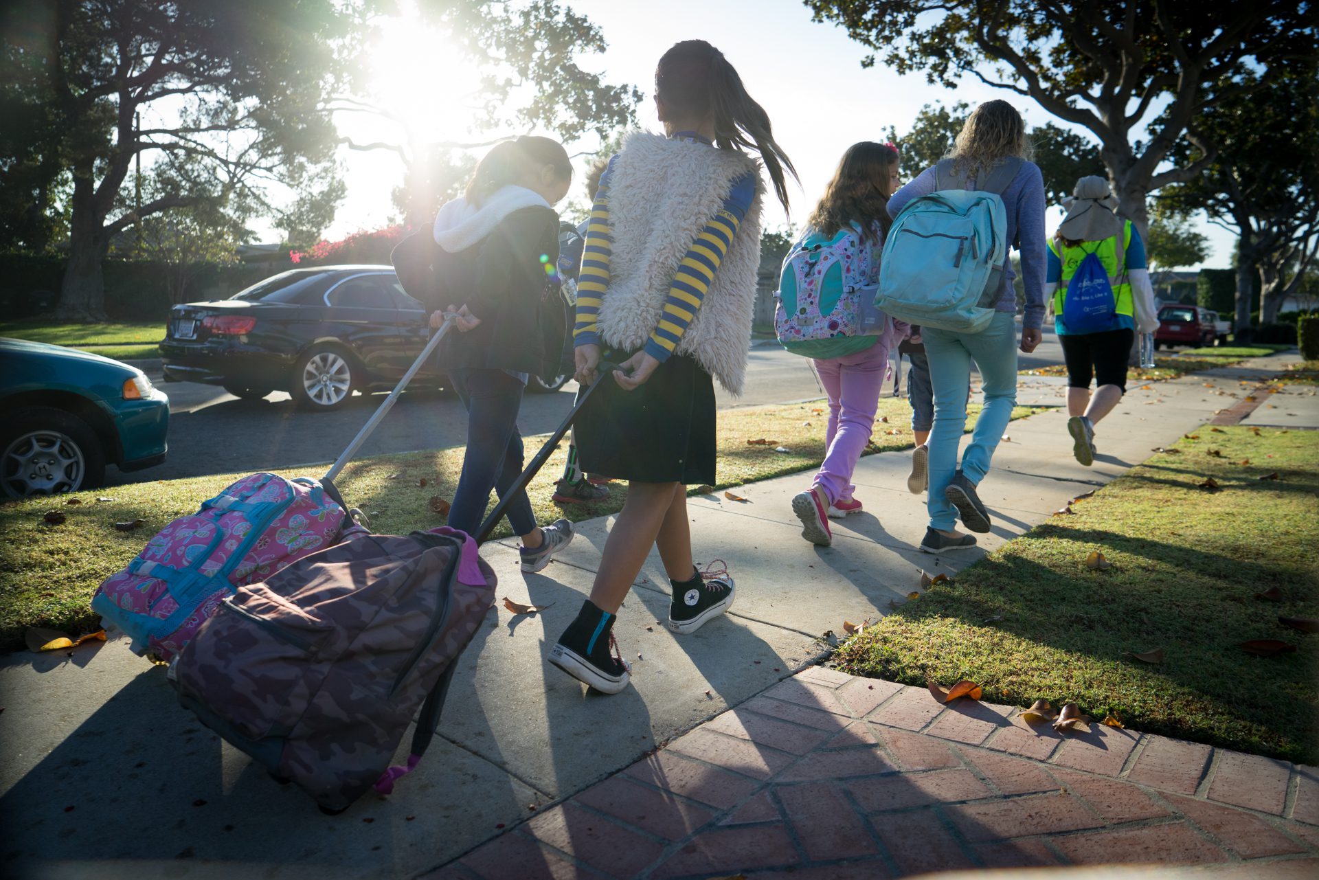 Children walking on a sidewalk with their backpacks